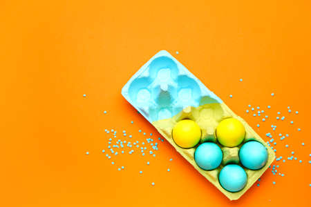 Holder with painted Easter eggs on color background