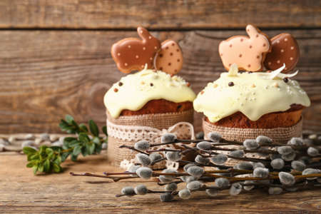 Willow branches and Easter cakes decorated with cookies on wooden background