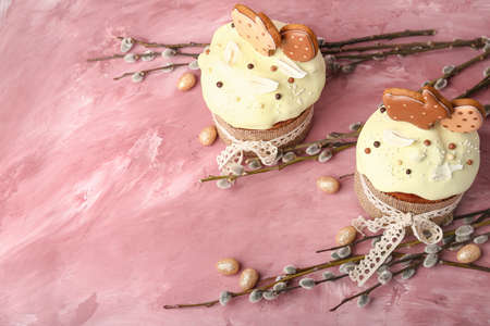 Willow branches, Easter cakes and painted eggs on pink background