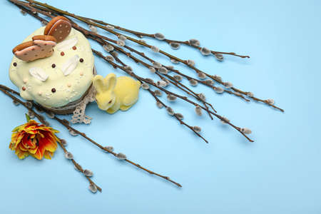 Willow branches, bunny, flower and Easter cake decorated with cookies on blue backgroundの写真素材