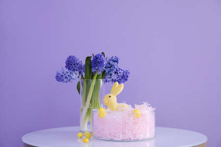 Easter bunny, eggs and vase with hyacinth flowers on table near color wallの写真素材