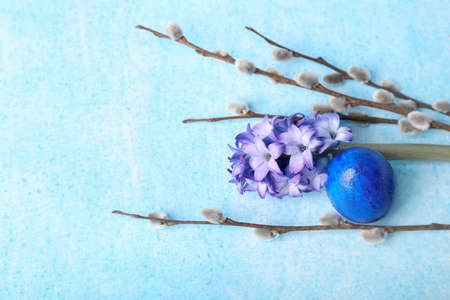 Willow branches, flowers and painted Easter egg on blue backgroundの写真素材