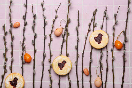 Willow branches, Easter cookies and painted eggs on pink tile backgroundの写真素材