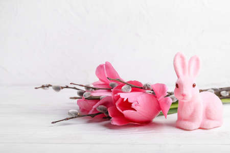 Willow branches, tulip flowers and Easter bunny on light wooden backgroundの写真素材