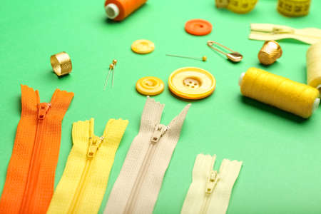 Set of colorful zippers and sewing supplies on green background