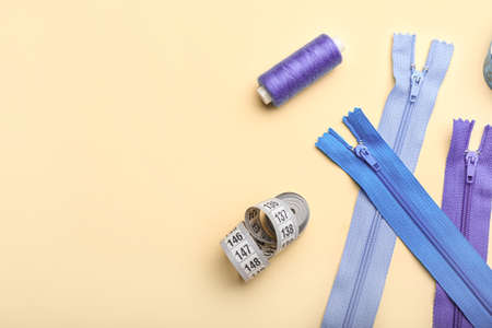 Set of colorful zippers and sewing supplies on beige background