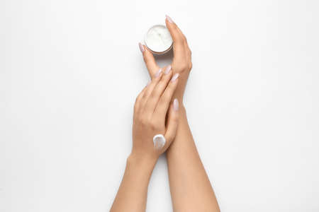 Woman with beautiful manicure holding jar of cream on white backgroundの写真素材