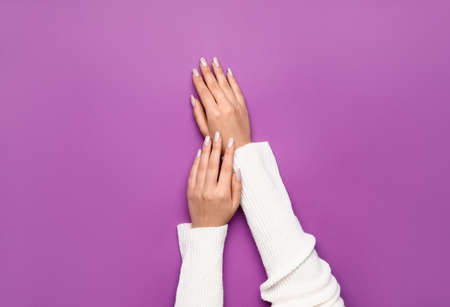 Female hands with beautiful manicure on purple backgroundの写真素材