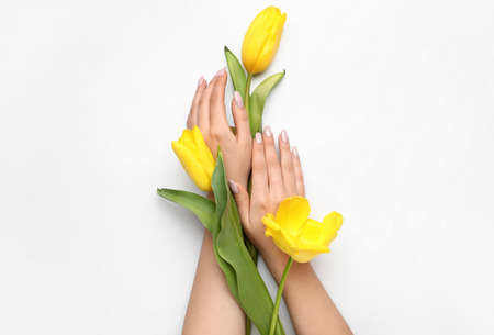Female hands with beautiful manicure and tulips on white backgroundの写真素材
