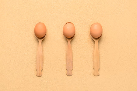 Spoons with fresh chicken eggs on beige backgroundの写真素材