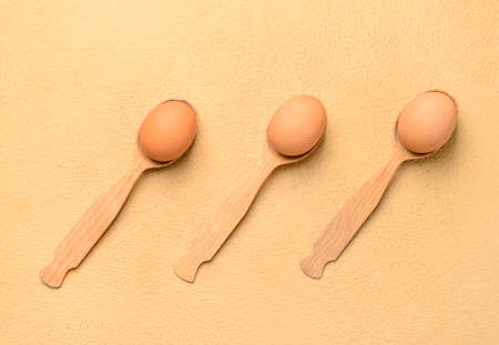 Spoons with fresh chicken eggs on beige backgroundの写真素材