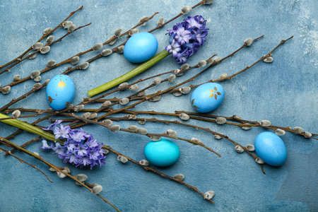 Pussy willow branches, painted Easter eggs and hyacinth flowers on blue backgroundの写真素材