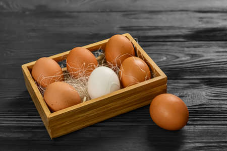 Box with fresh chicken eggs on black wooden background