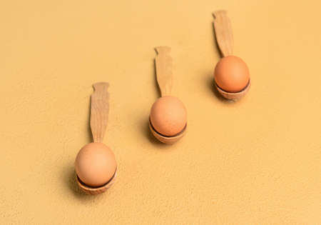 Spoons with fresh chicken eggs on beige backgroundの写真素材