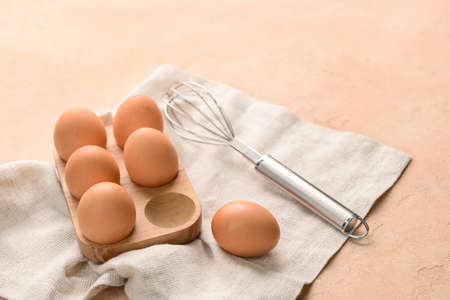 Holder with fresh chicken eggs and whiskey on beige background