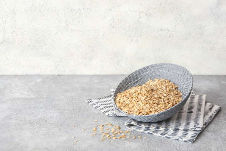 Wicker bowl of raw oatmeal on tableの写真素材