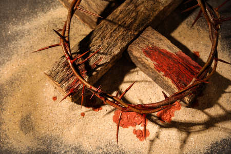 Crown of thorns with wooden cross and blood drops on sandの写真素材