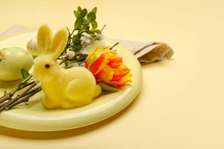 Plate with beautiful tulip flowers, pussy willow branches and painted Easter eggs on yellow background, closeupの写真素材