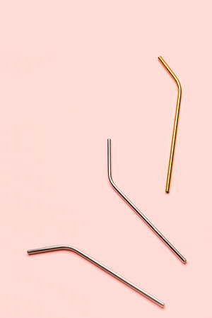 Stylish metal straws for drinks on pink background