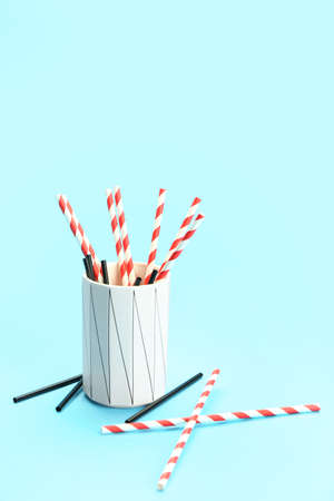 Cup with stylish straws for drinks on blue backgroundの写真素材