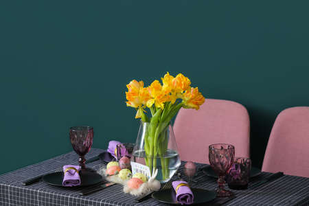 Beautiful setting with tulips on served table near green wallの写真素材