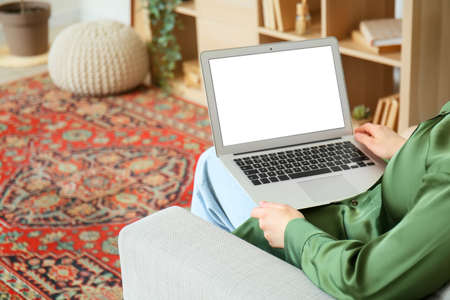 Woman with laptop sitting on sofa at home