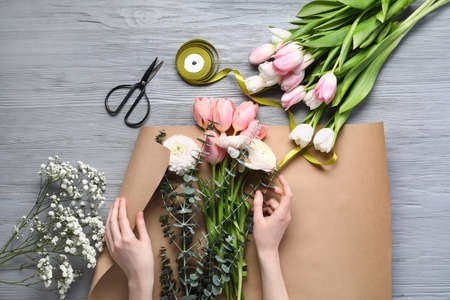 Woman making beautiful bouquet on gray wooden backgroundの写真素材