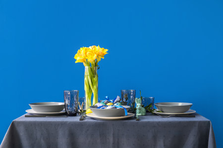 Table with beautiful setting served for Easter celebration near blue wallの写真素材