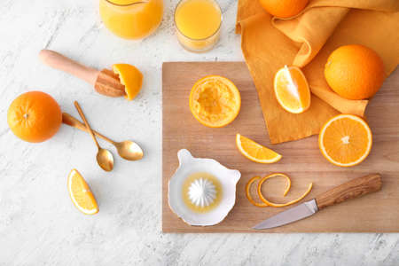 Ceramic juicer and oranges on light background