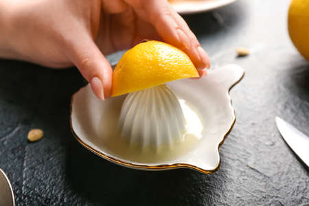 Woman squeezing fresh lemon on dark backgroundの写真素材