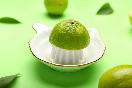 Ceramic juicer and limes on green background
