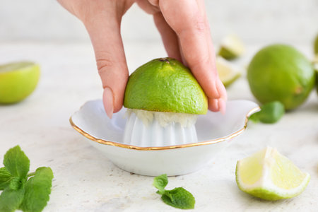 Woman squeezing fresh lime on light backgroundの写真素材