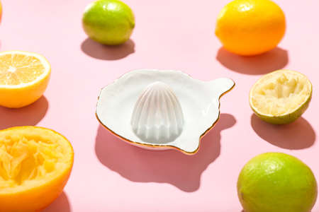 Ceramic juicer and citrus fruits on pink backgroundの写真素材