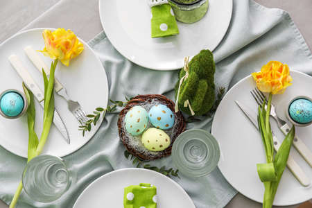 Beautiful table setting with Easter eggs and floral decor, closeup