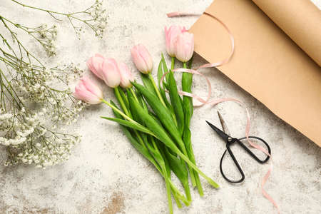 Composition with beautiful flowers, scissors and wrapping paper on light backgroundの写真素材
