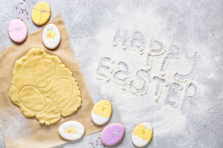 Fresh dough and tasty Easter cookies and text HAPPY EASTER on gray backgroundの写真素材