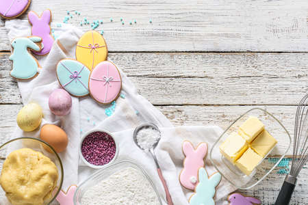 Bowl with dough, painted eggs and tasty Easter cookies on white wooden backgroundの写真素材