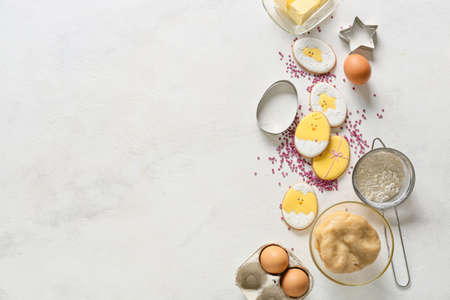 Tasty Easter cookies and ingredients on light background