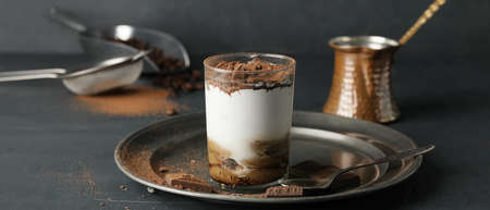 Sweet tasty tiramisu on dark table