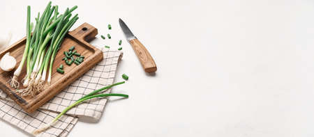 Cutting board, fresh green onion and knife on light background with space for textの写真素材