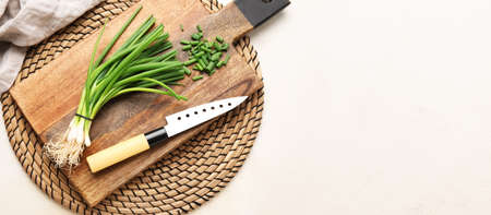 Cutting board, fresh green onion and knife on light background with space for textの写真素材