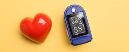 Red heart and pulse oximeter on yellow backgroundの写真素材