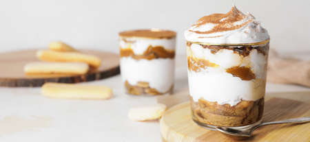 Glass with sweet tasty tiramisu on table
