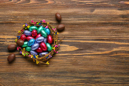 Composition with wreath and chocolate Easter eggs on wooden backgroundの写真素材