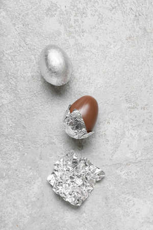 Chocolate eggs in foil on light background
