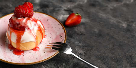 Plate with strawberry cinnamon roll on dark background with space for textの写真素材