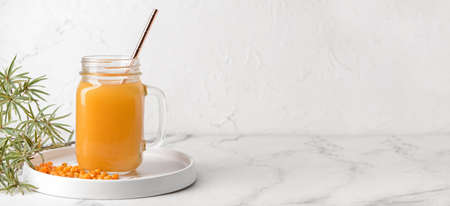 Mason jar of healthy sea buckthorn tea on white background with space for textの写真素材