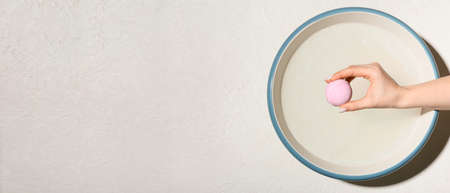 Female hand with bath bomb and bowl of water on white background with space for text