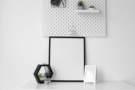 Blank frames, reed diffuser and planter on table near light wallの写真素材