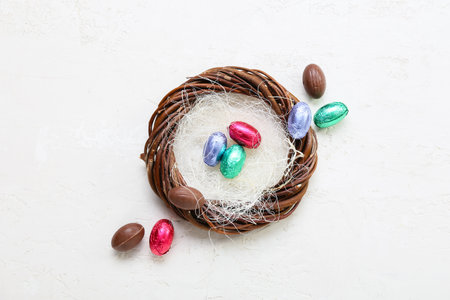 Composition with nest and chocolate Easter eggs on light background
